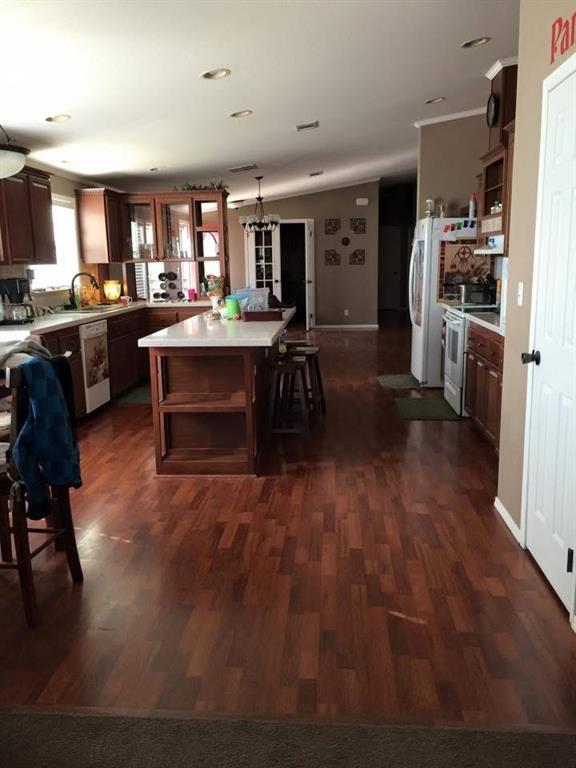 kitchen featuring white appliances, a center island, decorative light fixtures, dark hardwood / wood-style flooring, and a breakfast bar