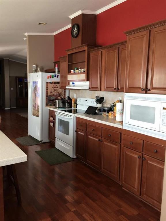 kitchen with decorative backsplash, white appliances, dark hardwood / wood-style floors, and crown molding