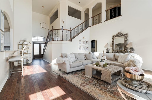 living room with an inviting chandelier, dark hardwood / wood-style flooring, and a high ceiling