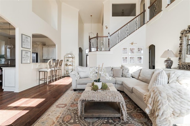 living room featuring a towering ceiling and dark wood-type flooring