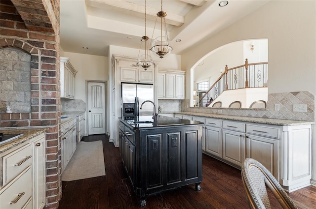 kitchen featuring light stone countertops, a kitchen island with sink, and decorative backsplash