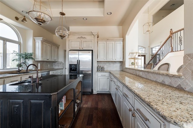 kitchen featuring tasteful backsplash, light stone counters, stainless steel fridge with ice dispenser, and hanging light fixtures