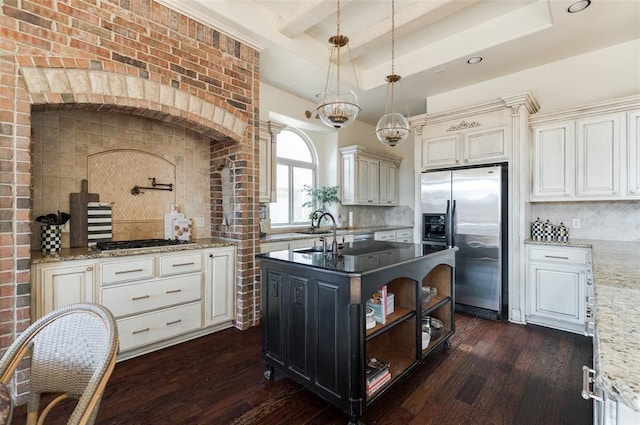 kitchen with hanging light fixtures, dark stone countertops, appliances with stainless steel finishes, a tray ceiling, and a kitchen island