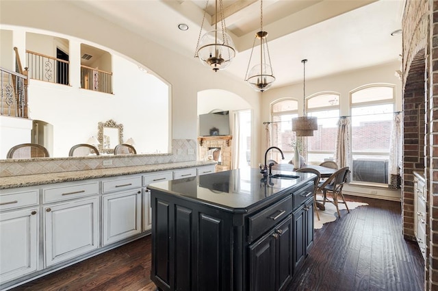 kitchen featuring a kitchen island with sink, sink, backsplash, and dark hardwood / wood-style floors