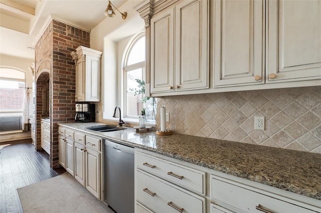 kitchen with a healthy amount of sunlight, sink, light stone countertops, and dishwasher