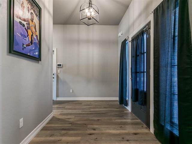 hallway with dark hardwood / wood-style flooring and a chandelier