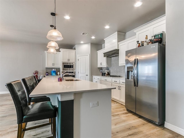 kitchen featuring appliances with stainless steel finishes, a breakfast bar, pendant lighting, and white cabinets