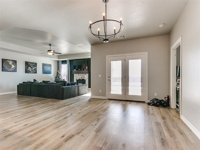 living room featuring ceiling fan with notable chandelier and light hardwood / wood-style floors