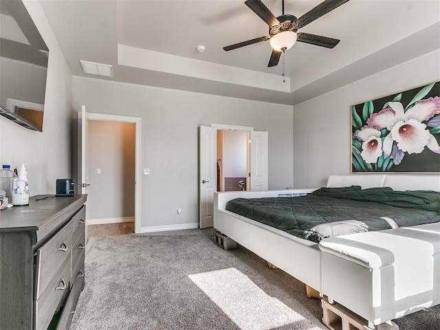 carpeted bedroom featuring ceiling fan and a tray ceiling