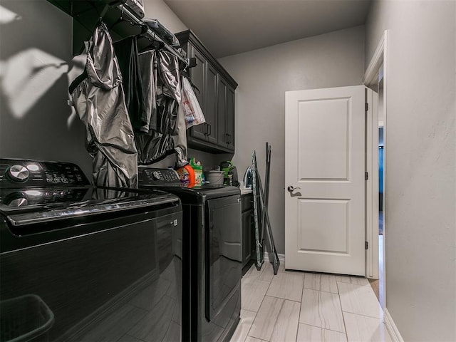 clothes washing area with separate washer and dryer and cabinets