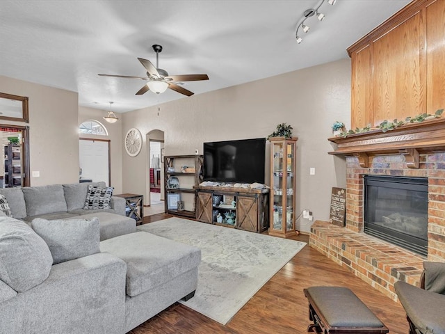 living room with a fireplace, wood-type flooring, rail lighting, and ceiling fan