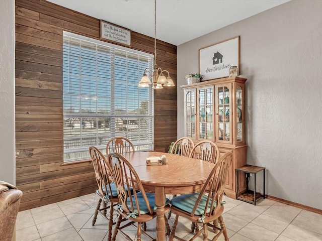 dining space featuring light tile patterned floors, a chandelier, and wood walls