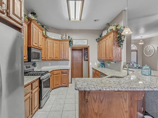 kitchen with sink, hanging light fixtures, kitchen peninsula, stainless steel appliances, and decorative backsplash