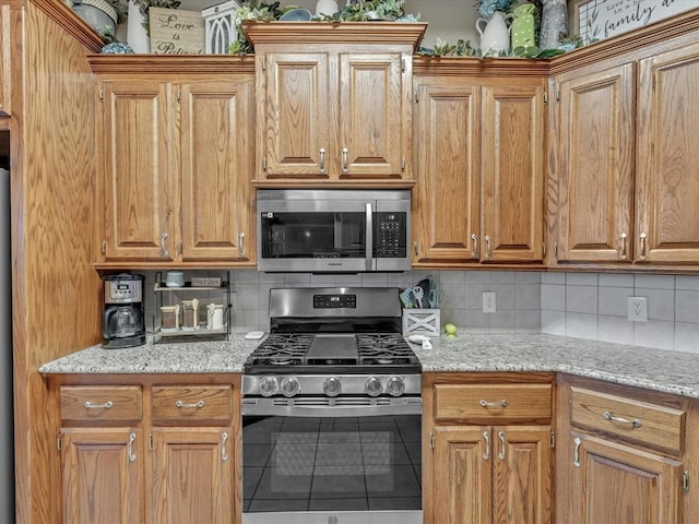 kitchen featuring light stone countertops, decorative backsplash, stainless steel appliances, and tile patterned floors