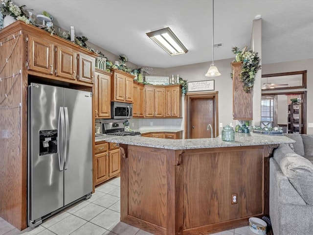 kitchen featuring light tile patterned floors, a peninsula, a breakfast bar, appliances with stainless steel finishes, and light stone countertops