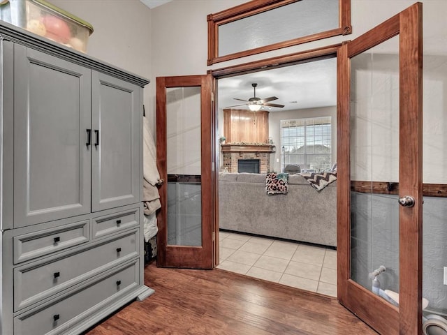 interior space with french doors, a fireplace, light wood finished floors, and ceiling fan