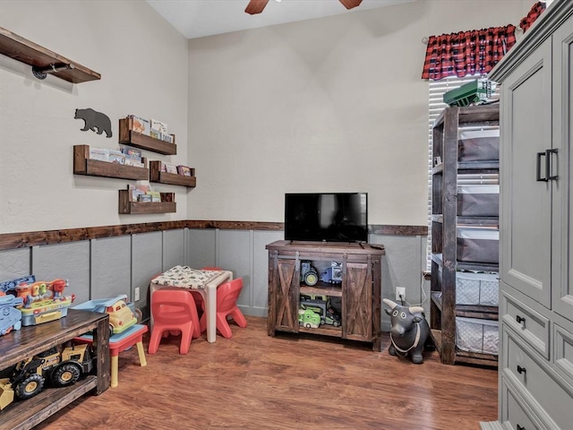 game room with ceiling fan, wainscoting, and wood finished floors