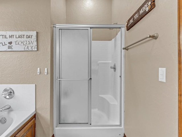 full bathroom with a textured wall and a shower stall