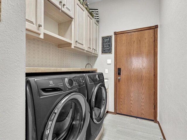 clothes washing area with cabinet space, baseboards, and washing machine and clothes dryer