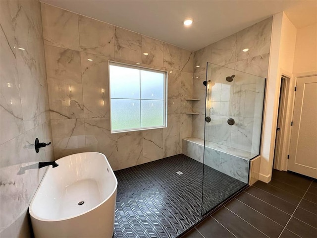 bathroom featuring shower with separate bathtub and tile walls