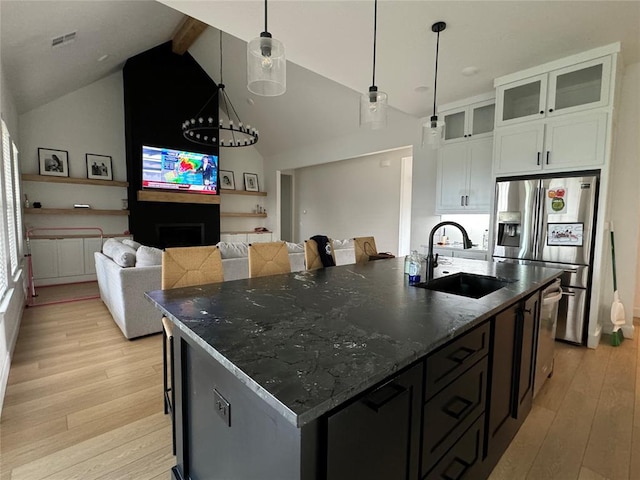 kitchen with pendant lighting, sink, white cabinets, a kitchen island with sink, and stainless steel refrigerator with ice dispenser