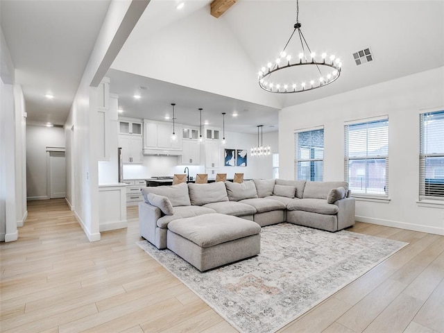 living room with beam ceiling, high vaulted ceiling, a chandelier, and light wood-type flooring