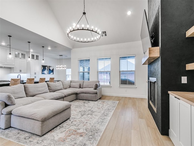 living room with a high ceiling, an inviting chandelier, and light wood-type flooring