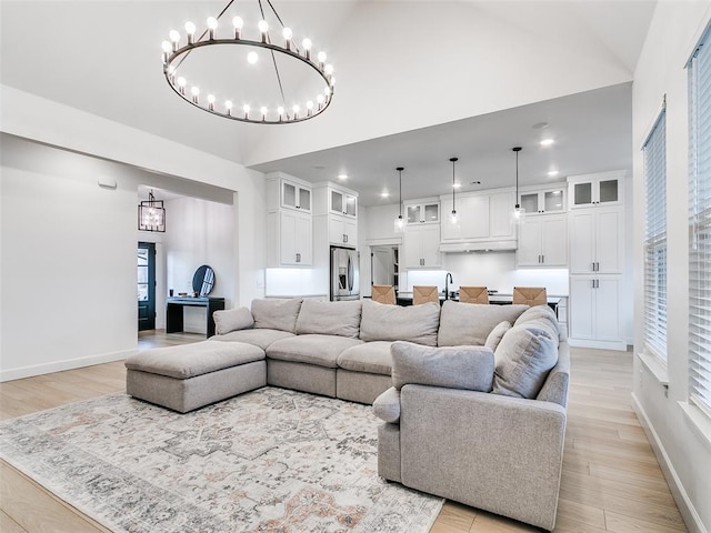 living room with vaulted ceiling, light hardwood / wood-style floors, and a chandelier