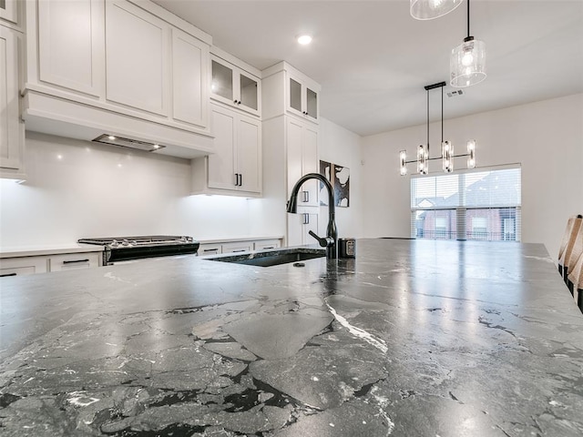 kitchen featuring pendant lighting, sink, white cabinetry, dark stone countertops, and stainless steel range