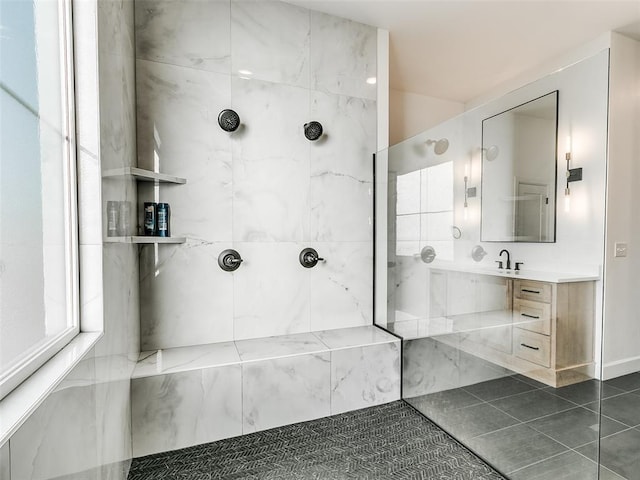 bathroom with tile patterned floors, vanity, and a tile shower