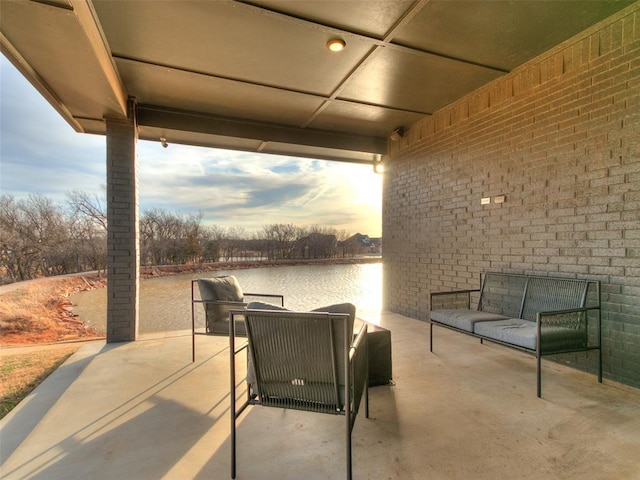 patio terrace at dusk with a water view and an outdoor living space