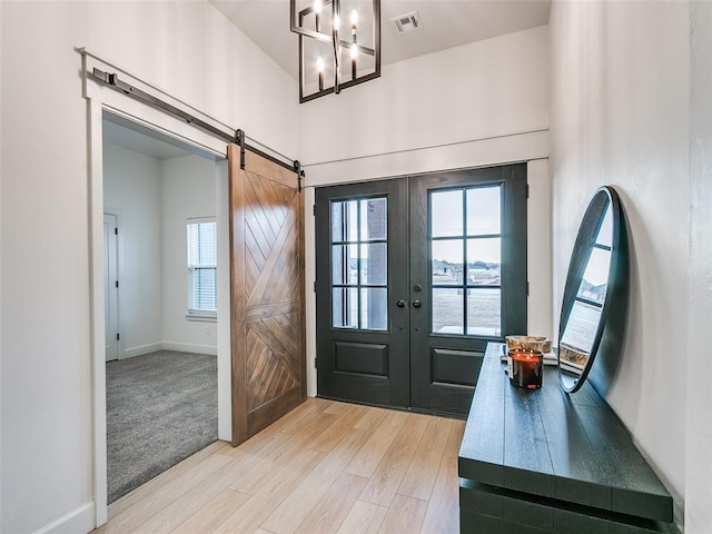 entrance foyer with a barn door, light hardwood / wood-style floors, and french doors