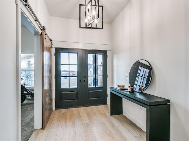 foyer featuring french doors, a barn door, and light hardwood / wood-style flooring