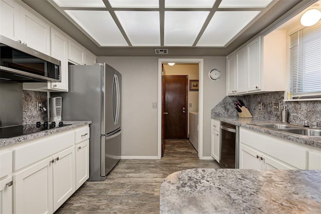 kitchen with appliances with stainless steel finishes, hardwood / wood-style floors, tasteful backsplash, white cabinetry, and sink