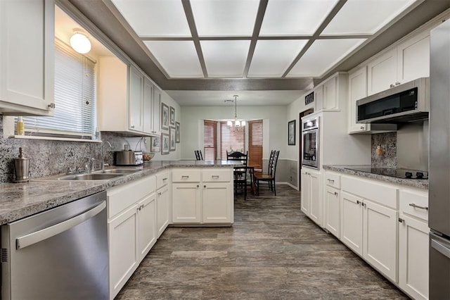 kitchen with decorative light fixtures, white cabinets, stainless steel appliances, dark wood-type flooring, and an inviting chandelier