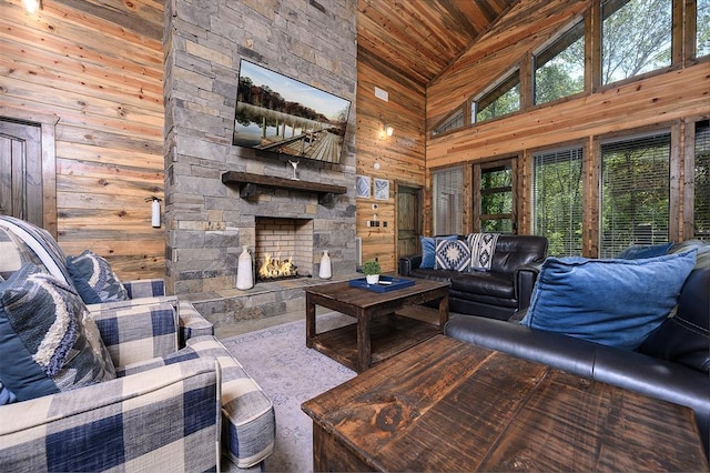 living area featuring high vaulted ceiling, wood walls, a fireplace, and wooden ceiling