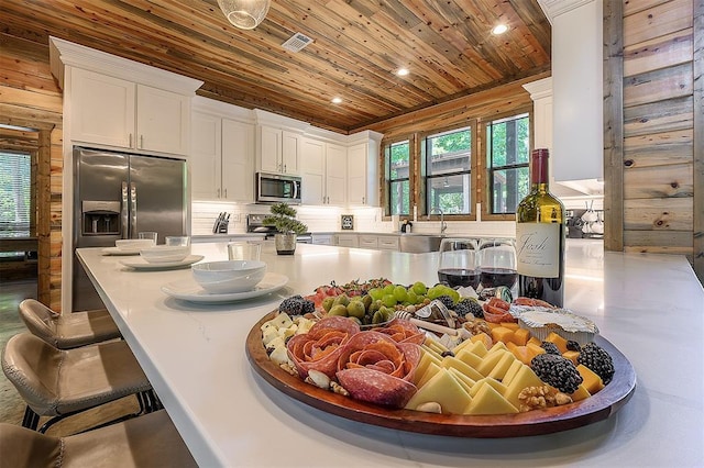 kitchen featuring appliances with stainless steel finishes, wooden ceiling, backsplash, and white cabinetry