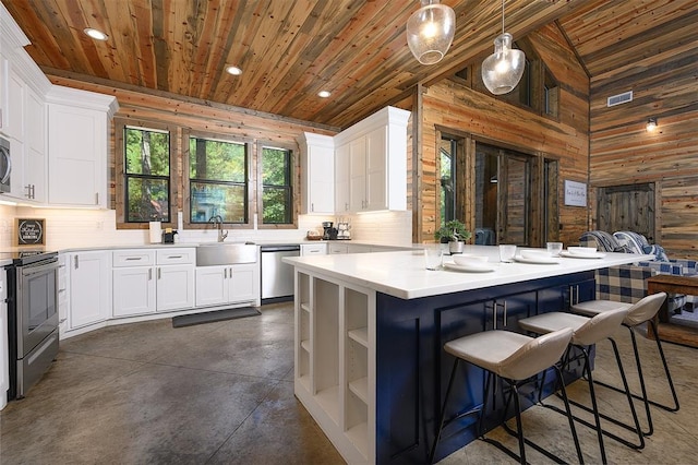 kitchen with wood ceiling, wooden walls, appliances with stainless steel finishes, and a sink