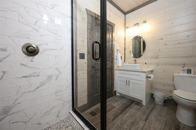 bathroom with toilet, wood finished floors, a shower stall, and vanity