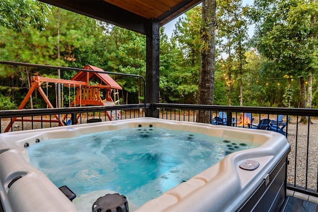 view of swimming pool with a playground and a hot tub