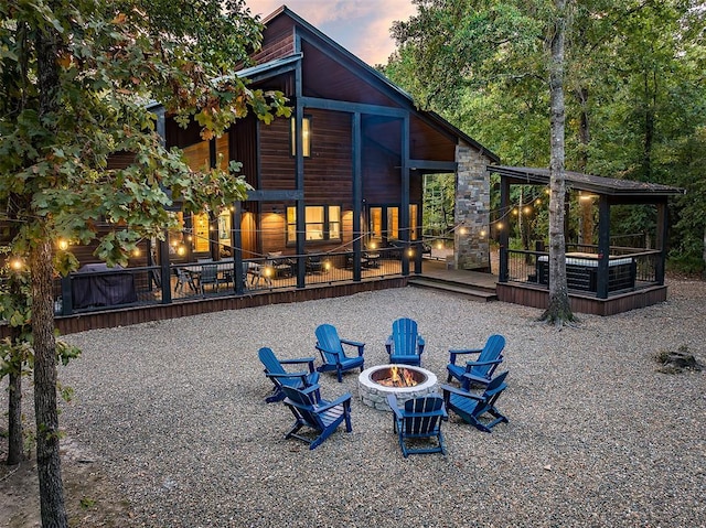 back of property with stone siding, a fire pit, and a deck