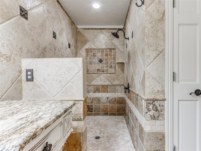 bathroom with tiled shower and vanity