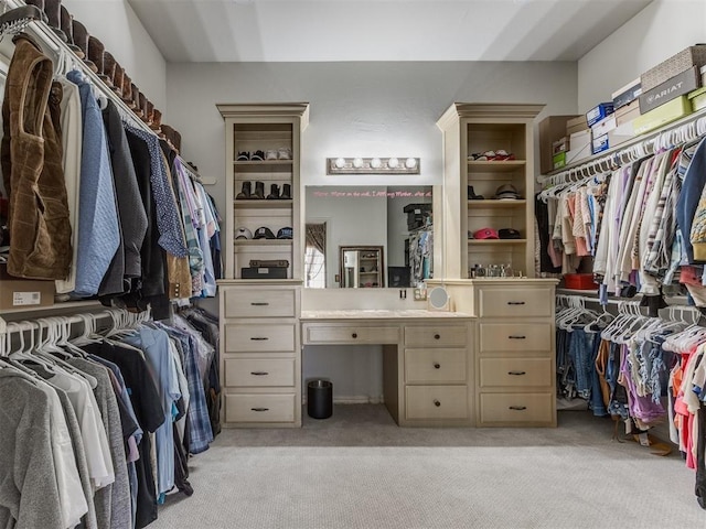 walk in closet with built in desk and light carpet