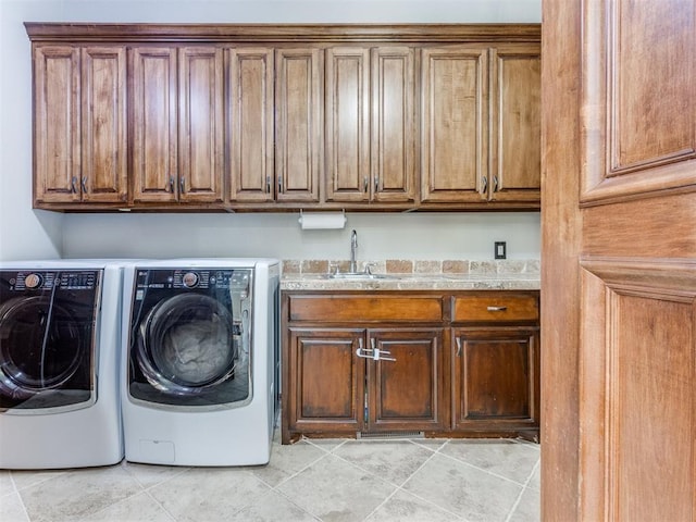 clothes washing area featuring washer and dryer, sink, and cabinets