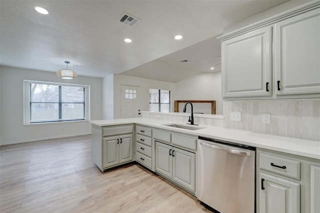 kitchen featuring sink, dishwasher, decorative backsplash, kitchen peninsula, and light wood-type flooring