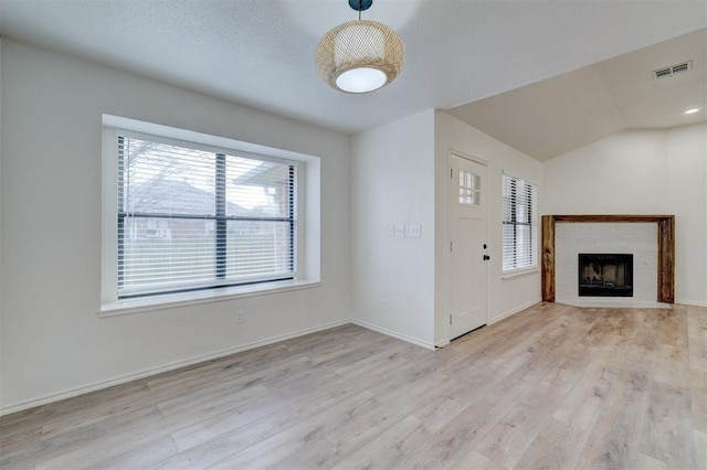 foyer featuring vaulted ceiling, a tile fireplace, and light wood-type flooring