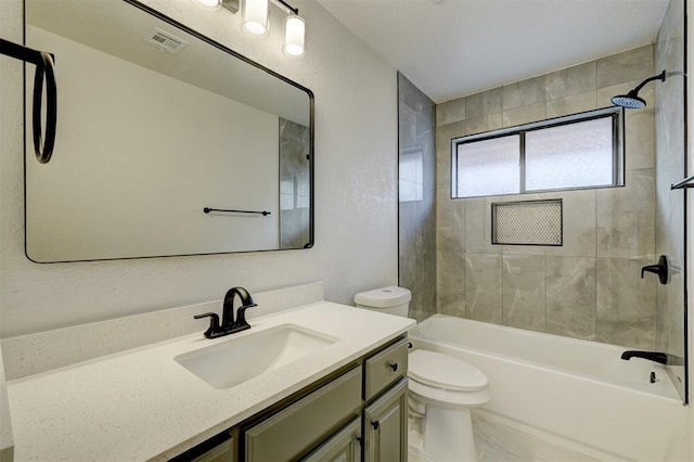 full bathroom featuring vanity, tiled shower / bath, and toilet