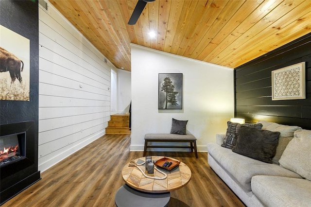 living room featuring hardwood / wood-style floors, wooden ceiling, a large fireplace, and wood walls