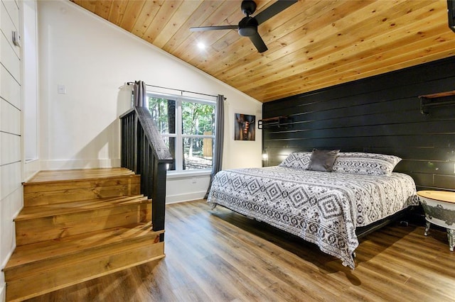 bedroom with vaulted ceiling, wood walls, hardwood / wood-style flooring, ceiling fan, and wooden ceiling