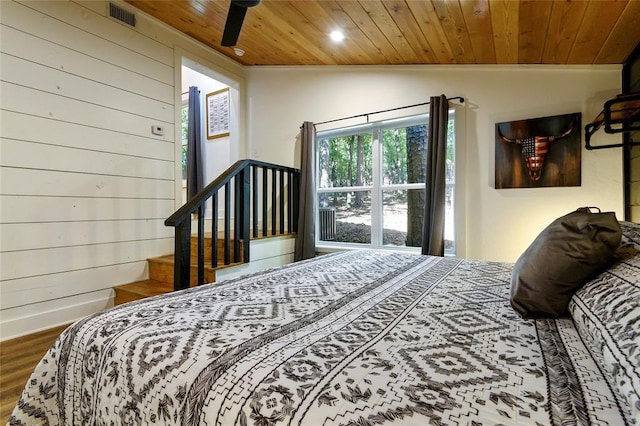 bedroom with hardwood / wood-style floors, wood walls, lofted ceiling, ceiling fan, and wooden ceiling